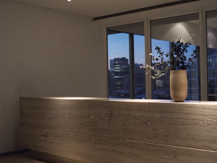 A calm clinic reception at dusk, the city beyond the glass